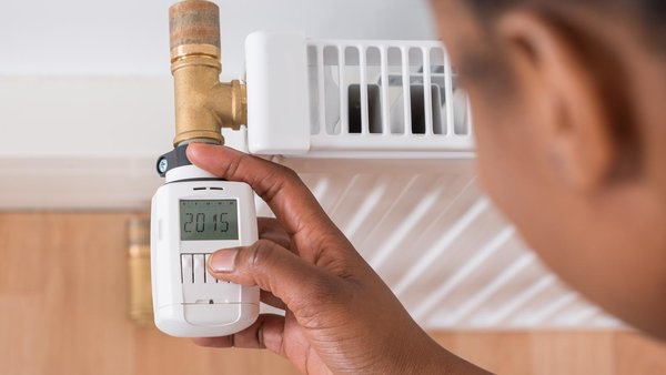 Nahaufnahme einer Person, die ein Thermostat einstellt