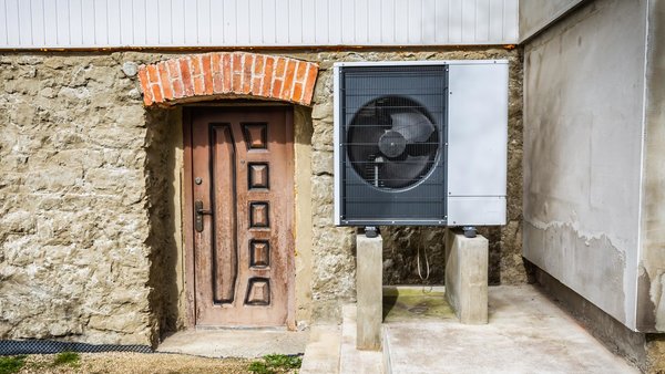 Wärmepumpe vor einem alten, unsanierten Haus